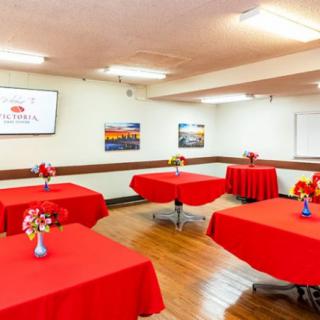 A well-decorated conference room featuring red tablecloths and floral centerpieces on each table, set up for an event or meeting.