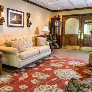 A cozy living room featuring a tufted sofa, ornate rug, and elegant decor with wooden double doors in the background.