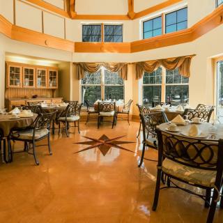 A well-appointed dining room with several tables and chairs, featuring large windows and wooden accents.