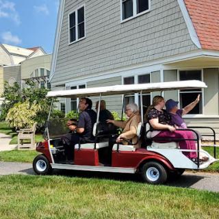 A group of people enjoying a ride in a golf cart outside a residential building.