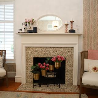 A cozy living room featuring a stylish fireplace adorned with flowers and a decorative mirror.