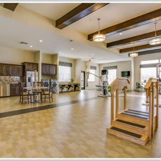 A spacious rehabilitation center featuring gym equipment, a kitchen area, and modern lighting.