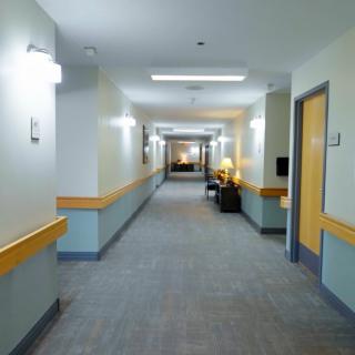 A clean and well-lit hospital hallway with doors leading to various rooms.