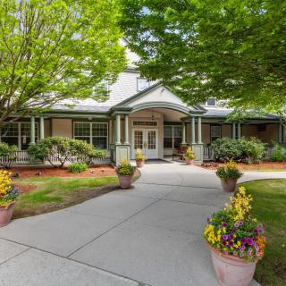 A charming house exterior with a well-maintained front yard and landscaping, featuring a pathway flanked by potted plants.
