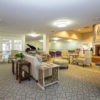 A spacious and elegantly designed living room with a seating area, piano, and fireplace.