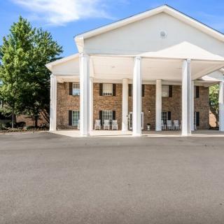 This image shows the exterior of a hotel building with prominent white columns and a clear blue sky.