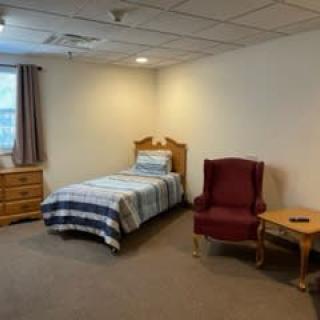 A simple bedroom with a single bed and basic furniture.