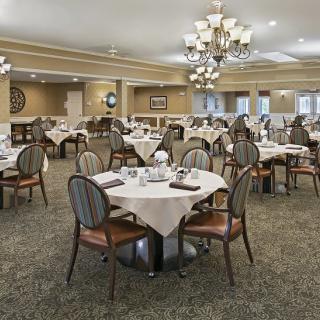 An elegant dining room with set tables and chandeliers.