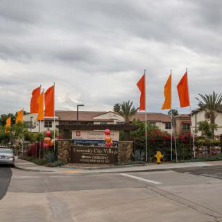 Entrance to a community with colorful flags and a cloudy sky.