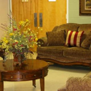 A cozy living room with a brown sofa, decorative pillows, and a wooden coffee table adorned with a floral arrangement.