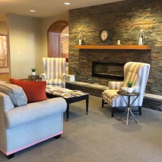 A cozy living room with modern decor, featuring a stone wall fireplace and comfortable seating.