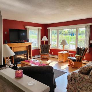A cozy living room with large windows, a television, and comfortable seating.