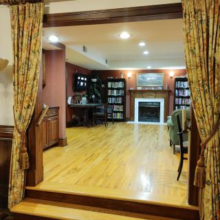 A cozy living room with hardwood floors, a fireplace, and bookshelves.