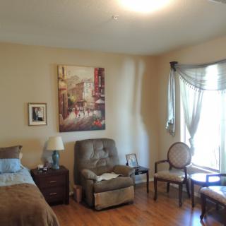 A cozy bedroom with an armchair and artwork displayed on the wall.