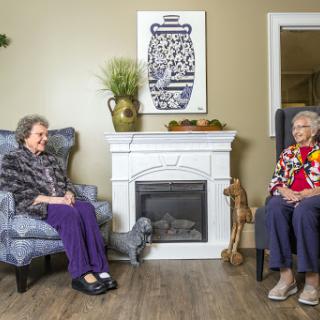 Two elderly women enjoying a conversation in a cozy living room setting.