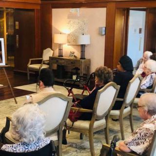 A group of elderly individuals attending a presentation in a cozy meeting room.
