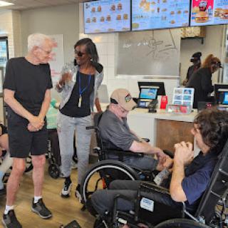 A lively scene at a fast food restaurant where individuals in wheelchairs are engaged in conversation with others.