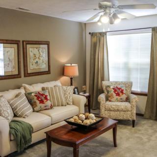 A cozy living room with a sofa, armchair, and warm decor.