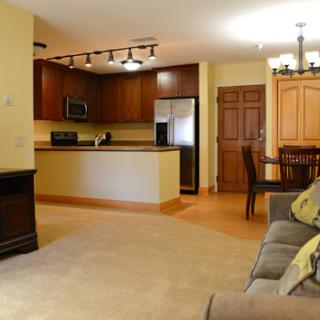 A cozy living room and kitchen area in a modern apartment, featuring warm colors and stylish furnishings.
