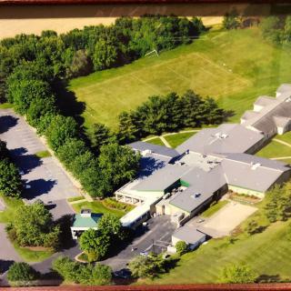 Aerial view of a large building complex surrounded by trees and greenery.