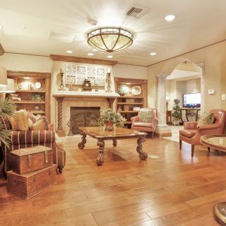 A warmly decorated living room featuring a fireplace, wood flooring, and traditional furnishings.