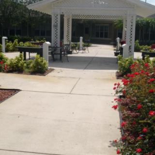 A serene garden walkway leading to a gazebo surrounded by lush landscaping and colorful flowers.