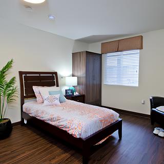 A modern, minimalist bedroom with a single bed and a wooden floor.
