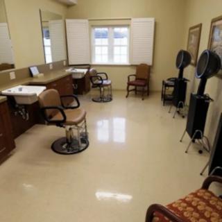 An empty hair salon with chairs, mirrors, and hair dryers.