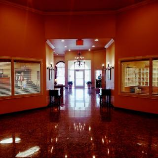 A spacious lobby with orange walls, featuring glossy floors and well-lit spaces, inviting visitors to explore further.