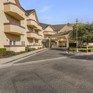 An exterior view of a hotel building with a parking area and main entrance.
