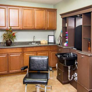 A cozy hair salon with a chair, sink, and wooden cabinetry.