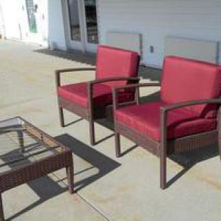 Outdoor patio setup with two red cushioned chairs and a glass-top table.