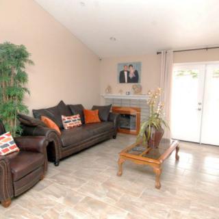 A cozy living room featuring a sofa, armchair, coffee table, and fireplace with decor pillows and artwork.