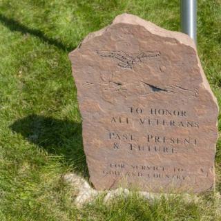 A memorial stone with engraved text on a grassy area.