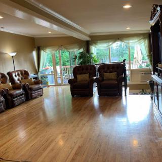 A spacious and inviting living room featuring comfortable chairs, a wooden floor, and large windows that bring in natural light.