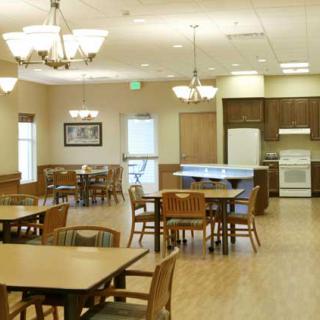 An empty dining area with tables and chairs, adjacent to a kitchen.