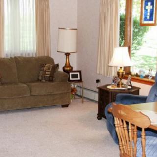 A cozy living room with a sofa, chair, and two lamps near a large window.