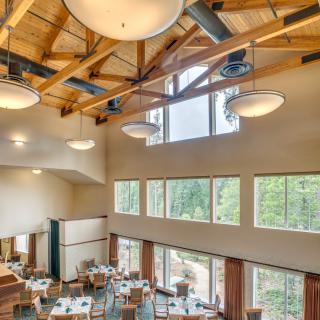 A spacious restaurant interior with wooden beams and large windows allowing natural light to illuminate the dining area.