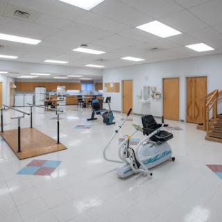 A spacious physical therapy room equipped with various exercise machines and rehabilitation tools.