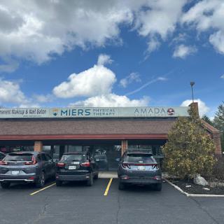 A view of a restaurant with cars parked in front under a partly cloudy sky.