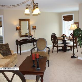 A cozy living room with elegant furniture and a dining area in the background.