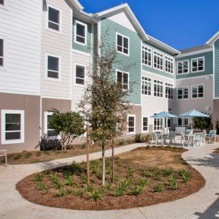 A modern residential apartment complex with a landscaped courtyard and outdoor seating area.
