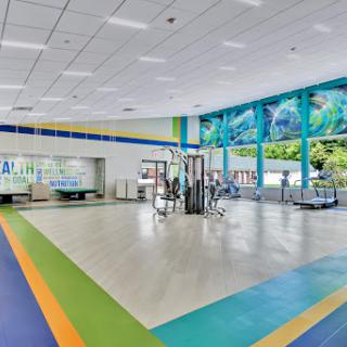 A bright and colorful modern lobby featuring a spacious waiting area with artistic wall design and large windows.
