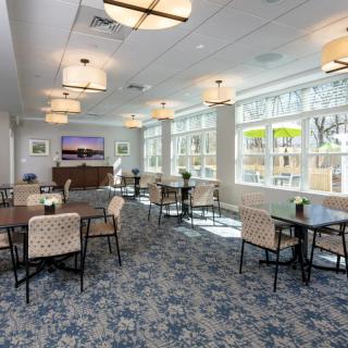 A modern dining area with tables, chairs, large windows and elegant lighting.
