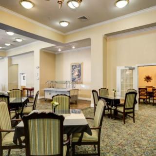 A spacious dining room with tables and chairs arranged neatly under soft lighting.