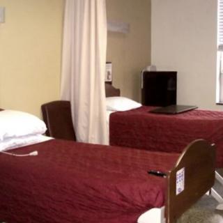 A hospital room with two neatly made beds separated by a privacy curtain.