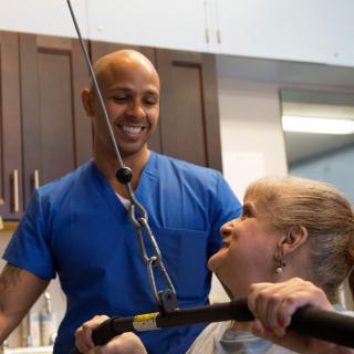 A healthcare professional assists a patient in physical therapy exercises.
