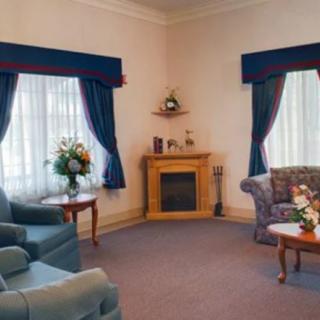 A cozy living room with sofas, a fireplace, and elegant curtains.