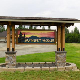 A wooden sign reading 'Sunset Home' with a landscape background.