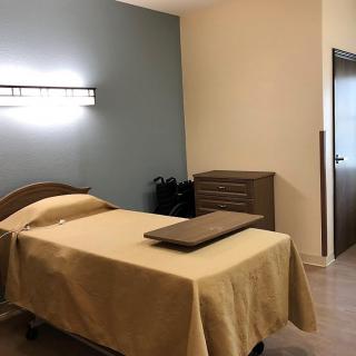 A serene massage room with a neatly made treatment bed and minimalist decor.